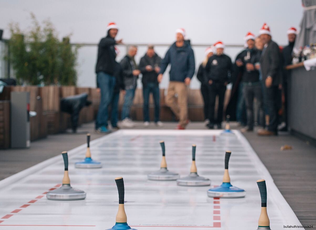 Frohes Beisammensein auf dem Eis: Besucher in Weihnachtsmann-Mützen genießen die gesellige Eisstockbahn der WeihnachtsMacherei