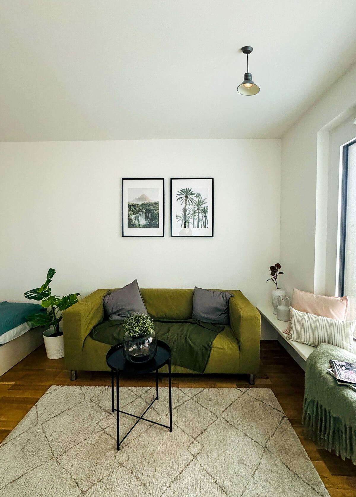Gemütlichkeit trifft auf Stil: Wohnbereich der Musterwohnung mit Sofa und sitzhoher Fensterbank.