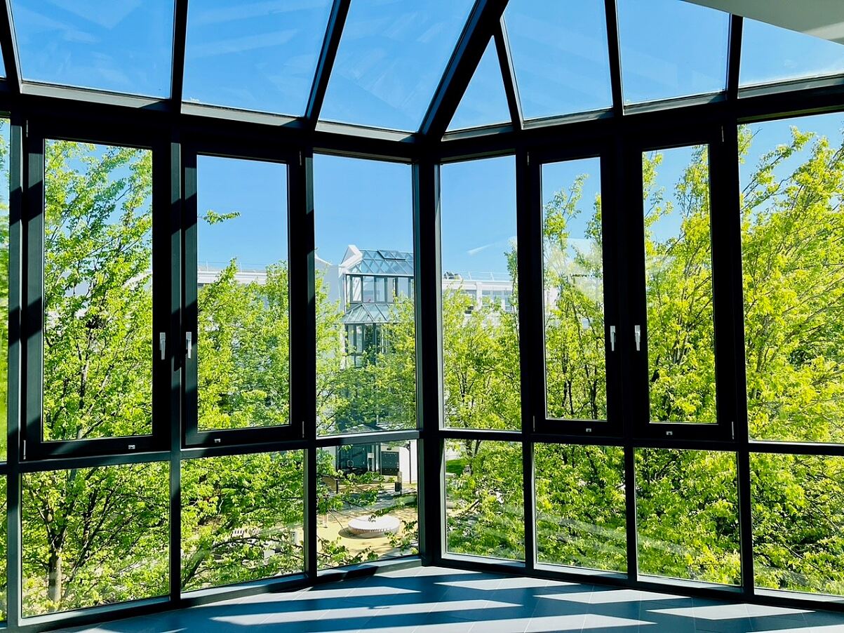 Blick ins Grüne: Vom verglasten Treppenhaus aus öffnet sich der Blick auf das üppige Blattwerk der Bäume im Innenhof – ein Moment der Ruhe.
