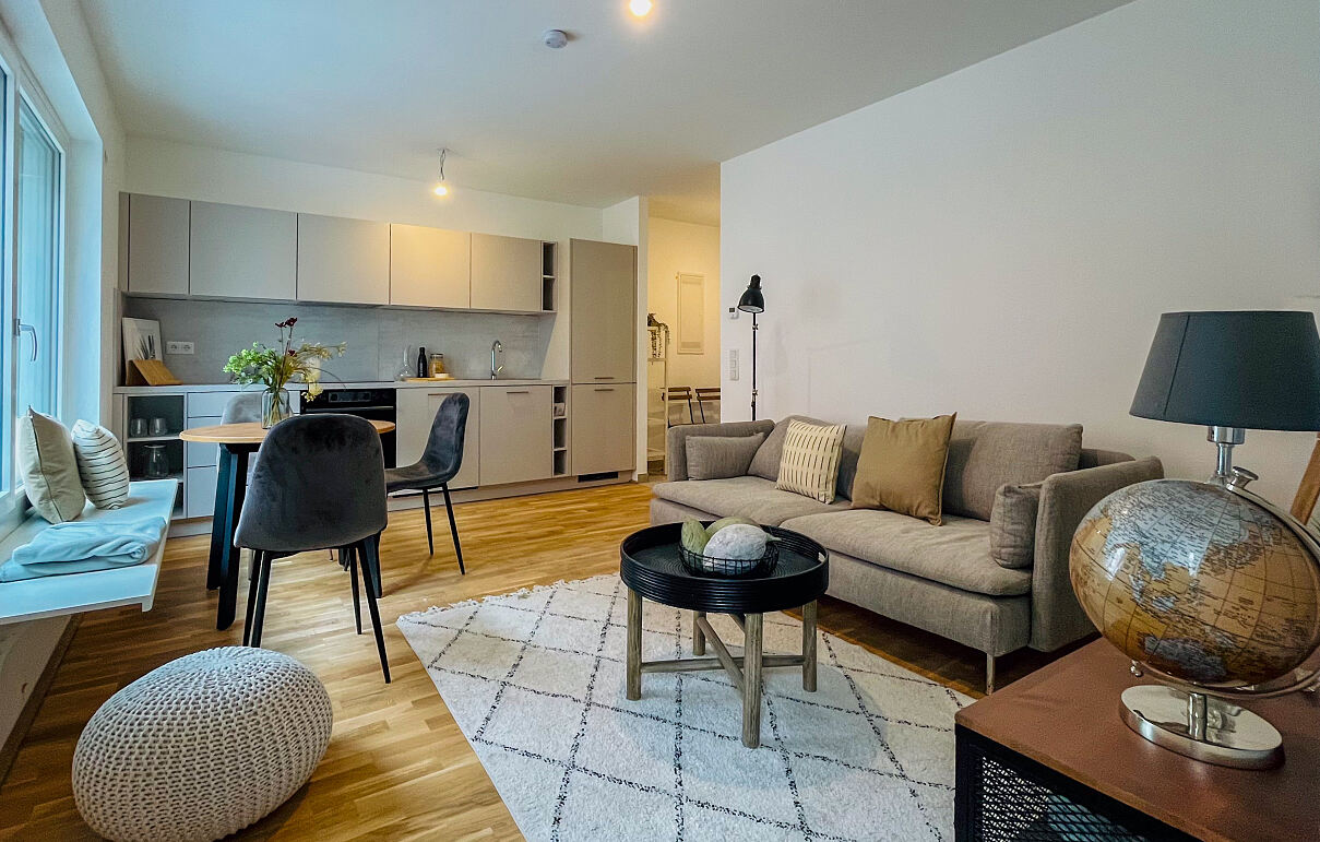 Die Wohnküche des „Kh:Ek:51“ bietet einen nahtlosen Übergang vom Kochbereich zum entspannenden Wohnbereich mit Sofa.